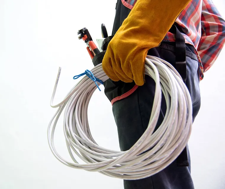 A local electrician carrying coiled wire and tools.